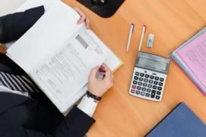 person-holding-book-with-calculator-on-table