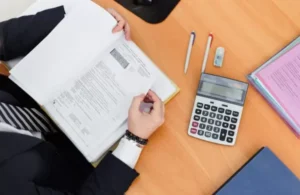 person-holding-book-with-calculator-on-table